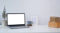 Laptop with white screen, coffee cup, house plant and boxes at home office desk. Royalty Free Stock Photo