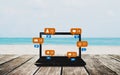 Computer laptop on wooden table at the beach in summer, with social media, social network notification icons Royalty Free Stock Photo