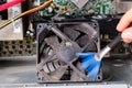 A computer master cleans the dust of the cooler of the ventilation of the system unit