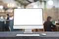 Computer monitor with white blank screen putting on wooden working desk, blurred restaurant as background Royalty Free Stock Photo