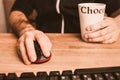 Computer mouse in hand and a cup of hot chocolate - remote work