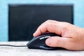 A computer mouse in a man`s hand near a monitor Royalty Free Stock Photo