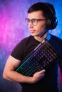 Computer nerd with keyboard over colorful pink and blue neon lit wall