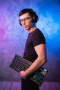 Computer nerd with keyboard over colorful pink and blue neon lit wall