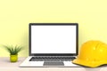 Safety helmet with laptop computer white blank screen on wood work table front view, Isolated on yellow background, 3D rendering Royalty Free Stock Photo