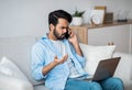 Computer Problems. Frustrated arab guy using cellphone and looking on laptop screen Royalty Free Stock Photo