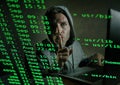 Computer programmer man in hoodie hacking system entering code typing on laptop hacking and decoding system data illegal access