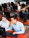 Computer science teacher supervises the execution of a programming task in a computer class