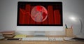 A computer screen displaying red world map and graphs sits on a desk Royalty Free Stock Photo