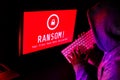 Computer screen with ransomware attack alert in red and a hacker