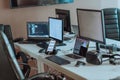 Computer screens running programming code in empty software developing agency office and computers parsing data