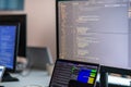 Computer screens running programming code in empty software developing agency office and computers parsing data