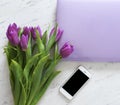 Computer, smartphone and a bouquet of purple tulips