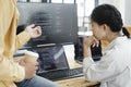 Team of young computer programmers cooperating while working on desktop PC in the office.