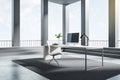 Computer standing on a desk in a bright room with black columns, stairs and big windows, black desktop, corner view. Work space Royalty Free Stock Photo