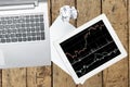 Computer, tablet with graph and paper on wood table Royalty Free Stock Photo