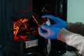 Computer technician in gloves safely repairing desktop hardware. Close-up view of hands fixing GPU and motherboard inside open PC Royalty Free Stock Photo