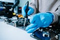 Computer technician in gloves safely repairing desktop hardware. Closeup view of hands fixing GPU and motherboard inside open PC Royalty Free Stock Photo