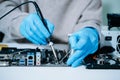Computer technician in gloves safely repairing desktop hardware. Closeup view of hands fixing GPU and motherboard inside open PC Royalty Free Stock Photo