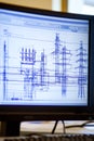 Computer workstation with CAD designs of high-voltage power lines displayed on dual screens.