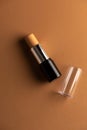 Concealer stick, on geometric backgrounds, in shades of brown. Product