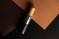 Concealer stick, on geometric backgrounds, in shades of brown. Product