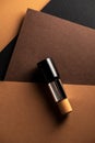 Concealer stick, on geometric backgrounds, in shades of brown. Product