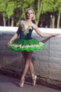 Concentrated Abashed Winsome Artistic Professional Caucasian Ballet Dancer in Green Tutu Dress Posing Near River in Summer Park