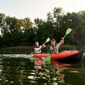 Concentrated adventurous young couple kayaking together in a lake on a late summer afternoon