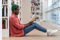 Concentrated African American student man with book spending free time in library, enjoying reading. Royalty Free Stock Photo