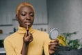 Concentrated african american woman applying lip gloss and looking Royalty Free Stock Photo