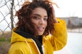 Concentrated african curly young lady wearing yellow coat