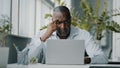 Concentrated african man employee american expert focused specialist sits in office works on laptop use personal Royalty Free Stock Photo