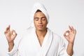 Concentrated african man in lotus position cropped. Meditating with closed eyes. Male in bathrobe and towel 