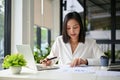 Concentrated Asian businesswoman analyzing financial data on reports, working in her office Royalty Free Stock Photo