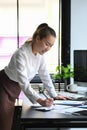 Concentrated asian businesswoman standing at her workplace and checking financial documents Royalty Free Stock Photo