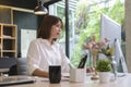 Concentrated asian female office worker working with computer at modern workplace