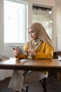 Concentrated Asian-Muslim woman is working on her digital tablet, working remotely at a coffee shop