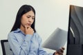 Concentrated asian woman brainstorming while coding data on desktop PC while working on computer codes in the office Royalty Free Stock Photo