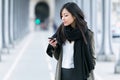 Concentrated asian young woman using her mobile phone in the street. Royalty Free Stock Photo