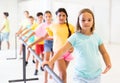 Assiduous preteen girl working near ballet barre during group choreography class Royalty Free Stock Photo