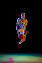 Concentrated athlete man, basketball player dribbling against black studio background in mixed neon light. Model Royalty Free Stock Photo