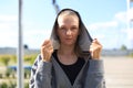 Concentrated athletic caucasian woman with a hood on her head wearing gray hoodie looking to the camera