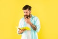 concentrated bearded man with book on yellow background, erudition