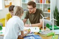 Concentrated bearded man in clear glasses sitting with his students