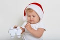 Concentrated blond haired infant studying his new toy, christmas present, holding in hands plastic dog toy, looking at it Royalty Free Stock Photo