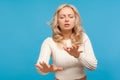 Concentrated blond woman in white knitted sweater trying to move with closed eyes and raised hands, vision problems, blindness