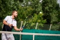 Young man in sportwear is playing tennis on out door court.