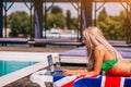 Concentrated Blondie Young Woman Is Laying On The Deck Chair And Typing On Her Laptop Near The Pool.