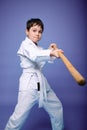 Concentrated boy - Aikido wrestler in a kimono practicing fighting skills with wooden jo weapon in his hands. Oriental martial